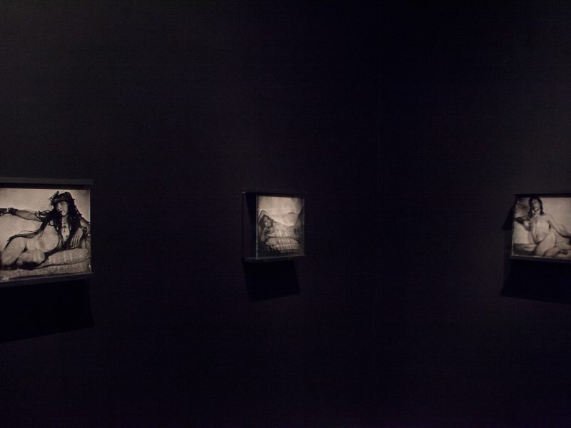Three ambrotypes float in a black walled room