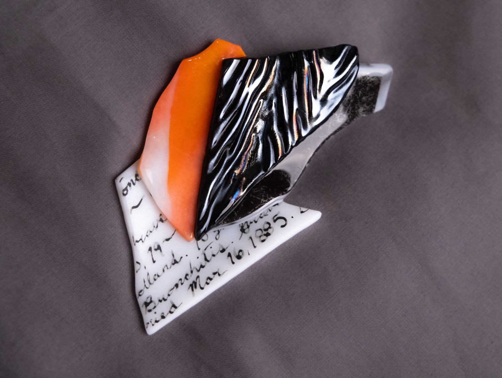 Fragments of colorful fused glass resting on a grey background