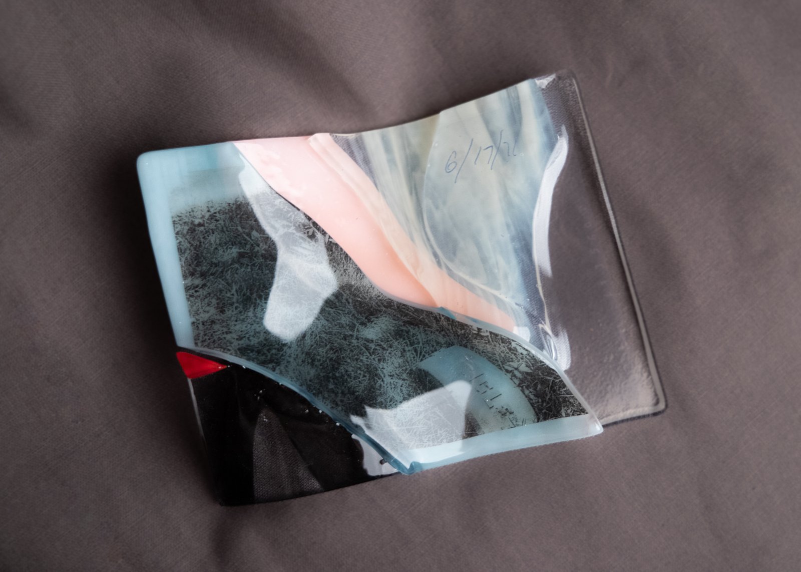 Fragments of colorful fused glass resting on a grey background