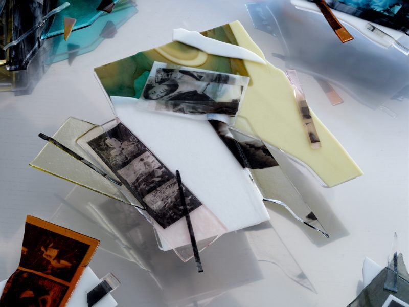Fragments of kiln-fused glass with self portraits of the artist sit in a stainless steel development tray.